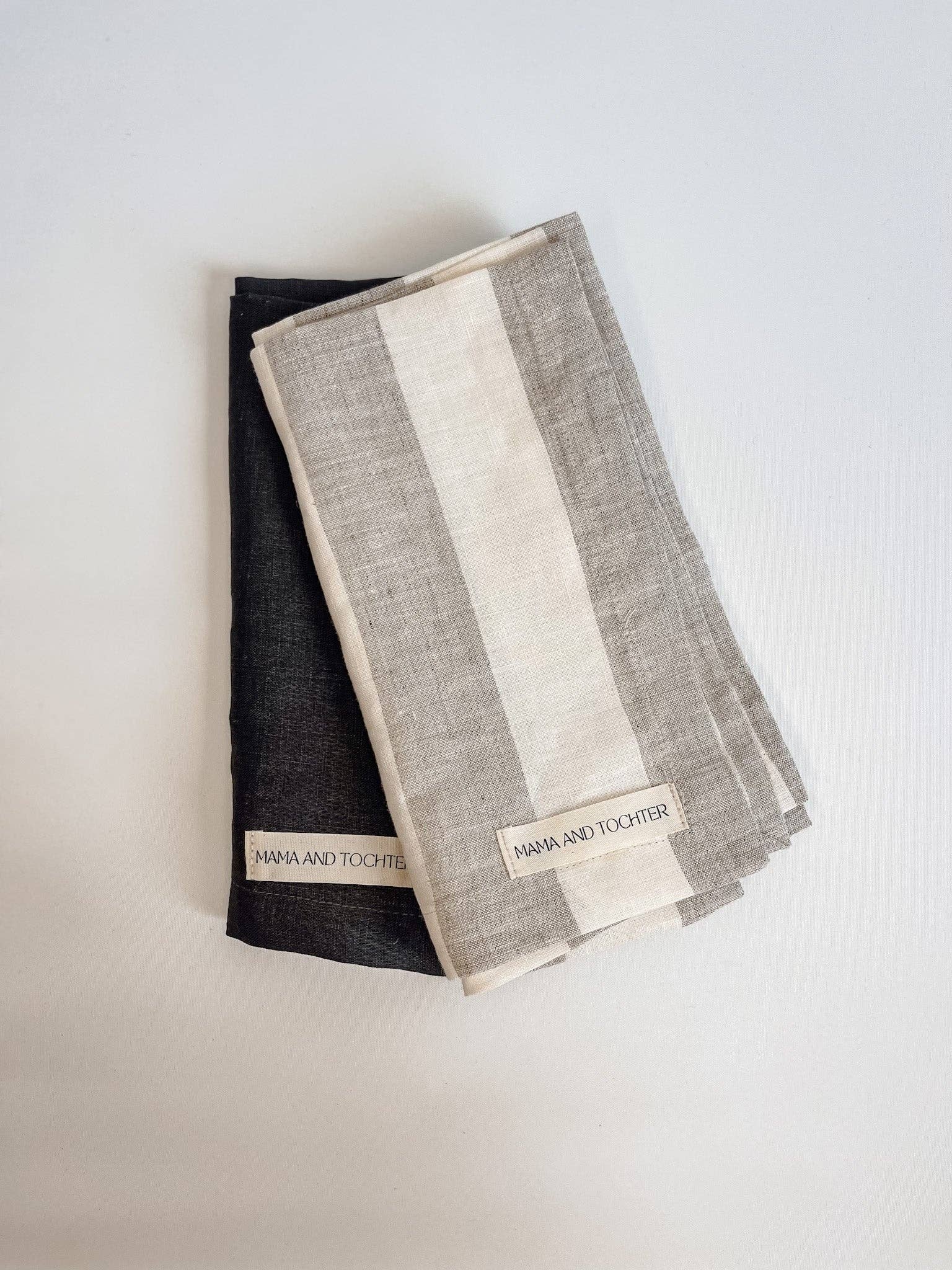 Two folded napkins, one black and one with a striped pattern, on a light gray background.
