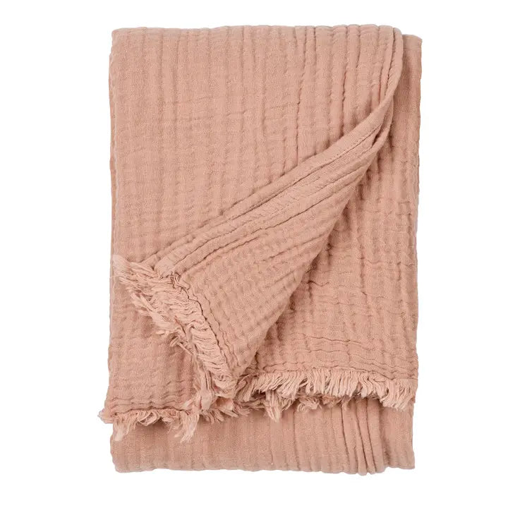 Pink textured blanket with frayed edges on a white background