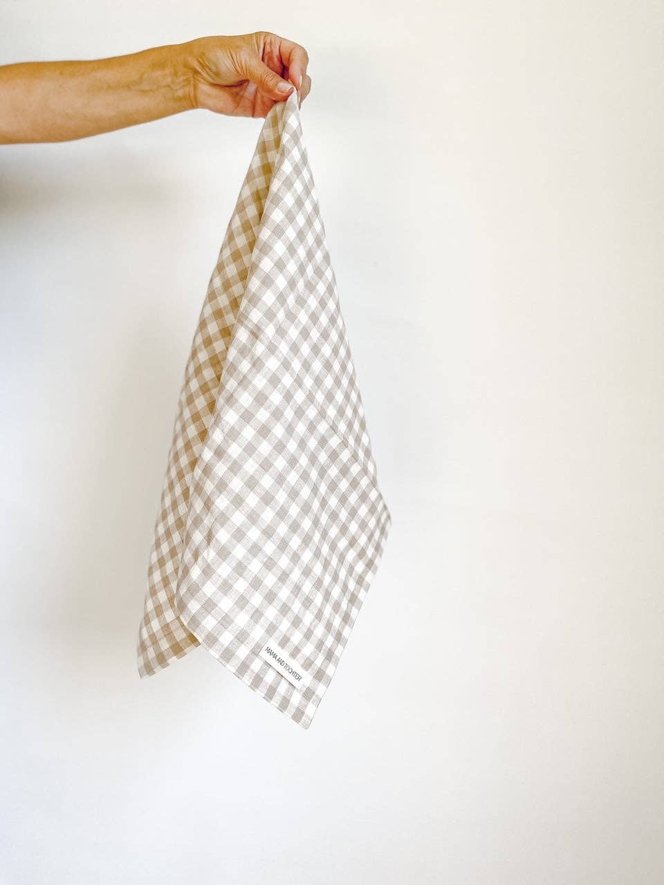 Hand holding a checkered towel against a plain background