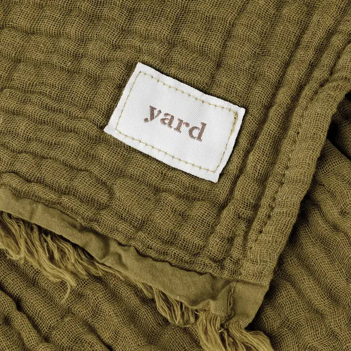 Close-up of a textured green fabric with a 'yard' label.