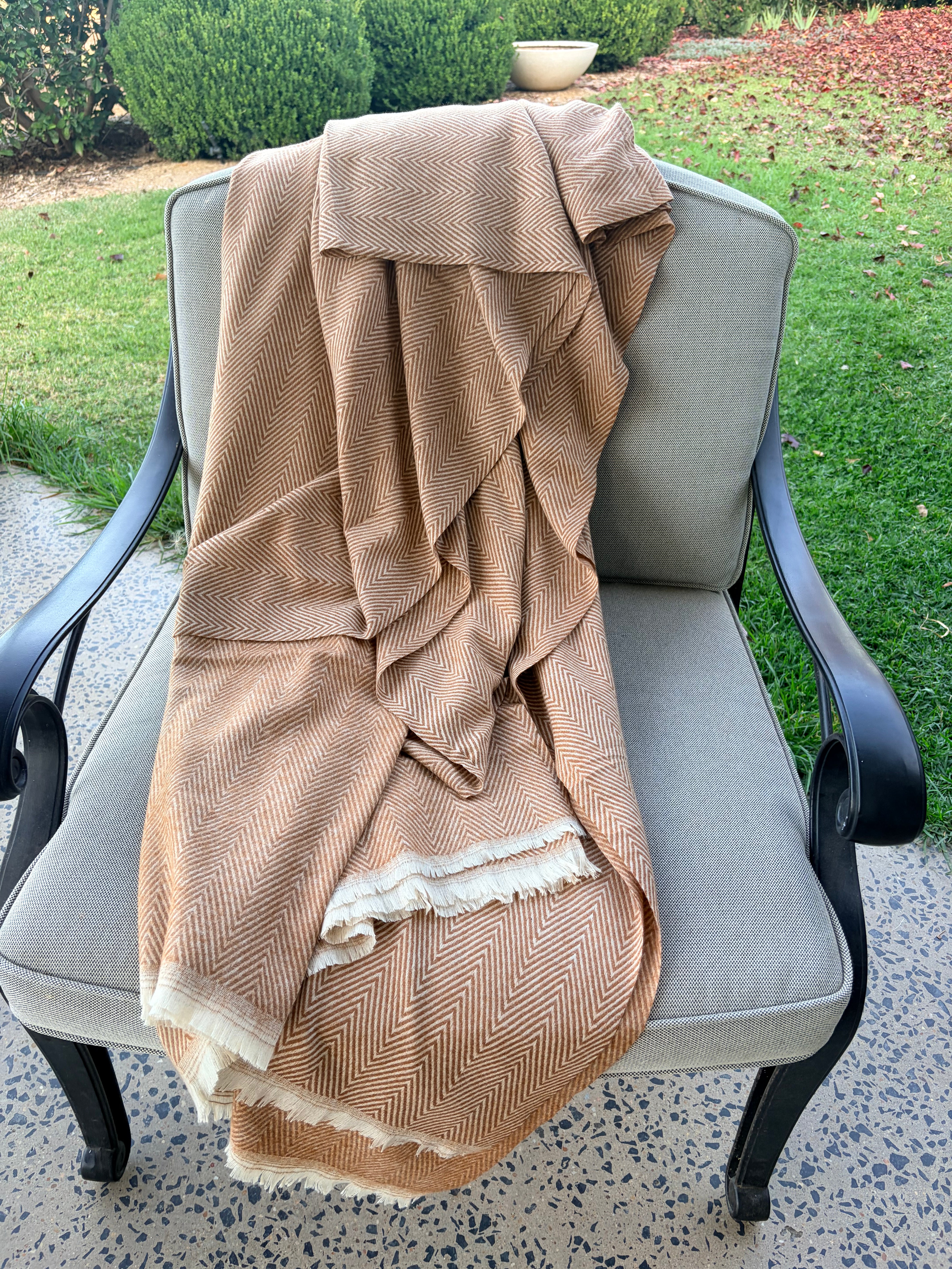 Beige textured throw draped over a chair outdoors on a patio.