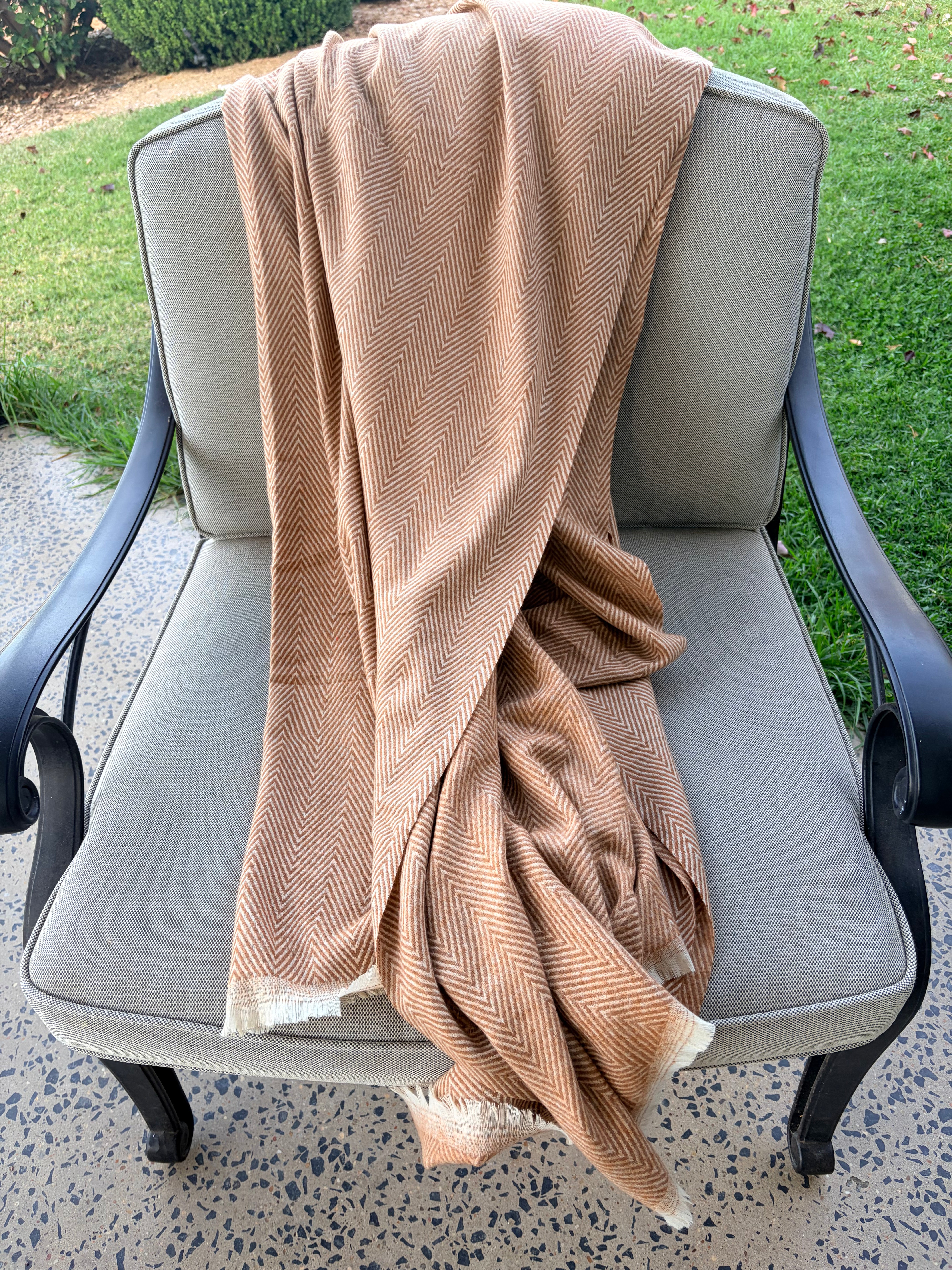 Beige throw draped over a gray chair outdoors on a patio.