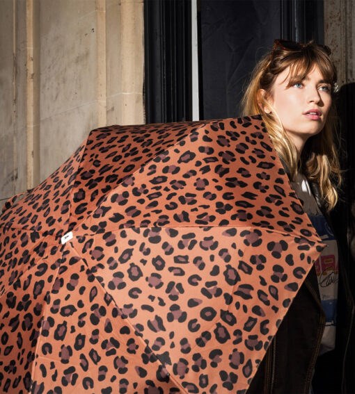 Woman holding a leopard print umbrella in an urban setting