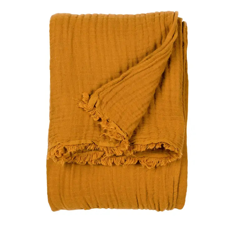 Mustard yellow textured blanket with frayed edges on a white background