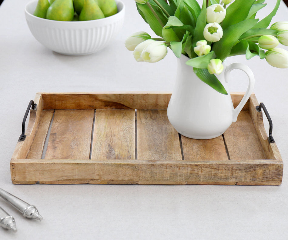 Wooden tray with a white pitcher of flowers on a light surface