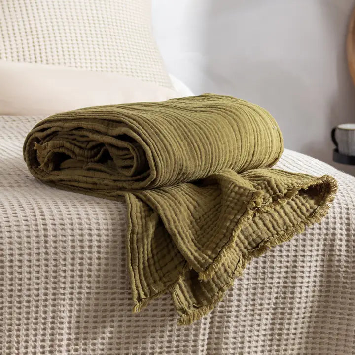 Folded green blanket on a textured surface with a blurred background