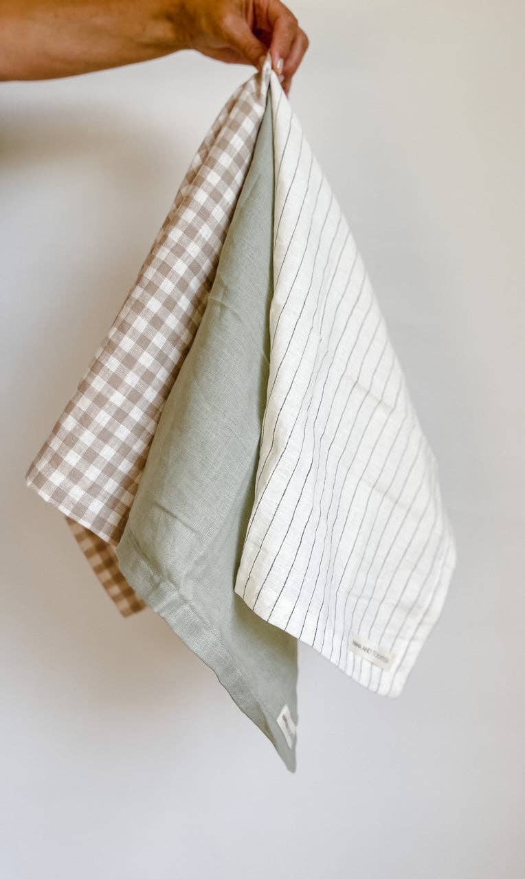 Hand holding a folded checkered towel against a plain background