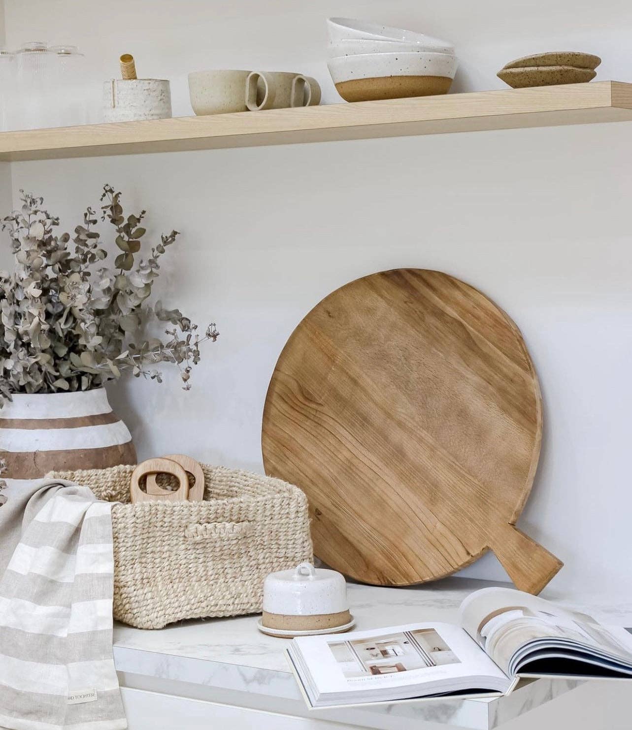 Wooden cutting board on a marble surface with a shelf in the background