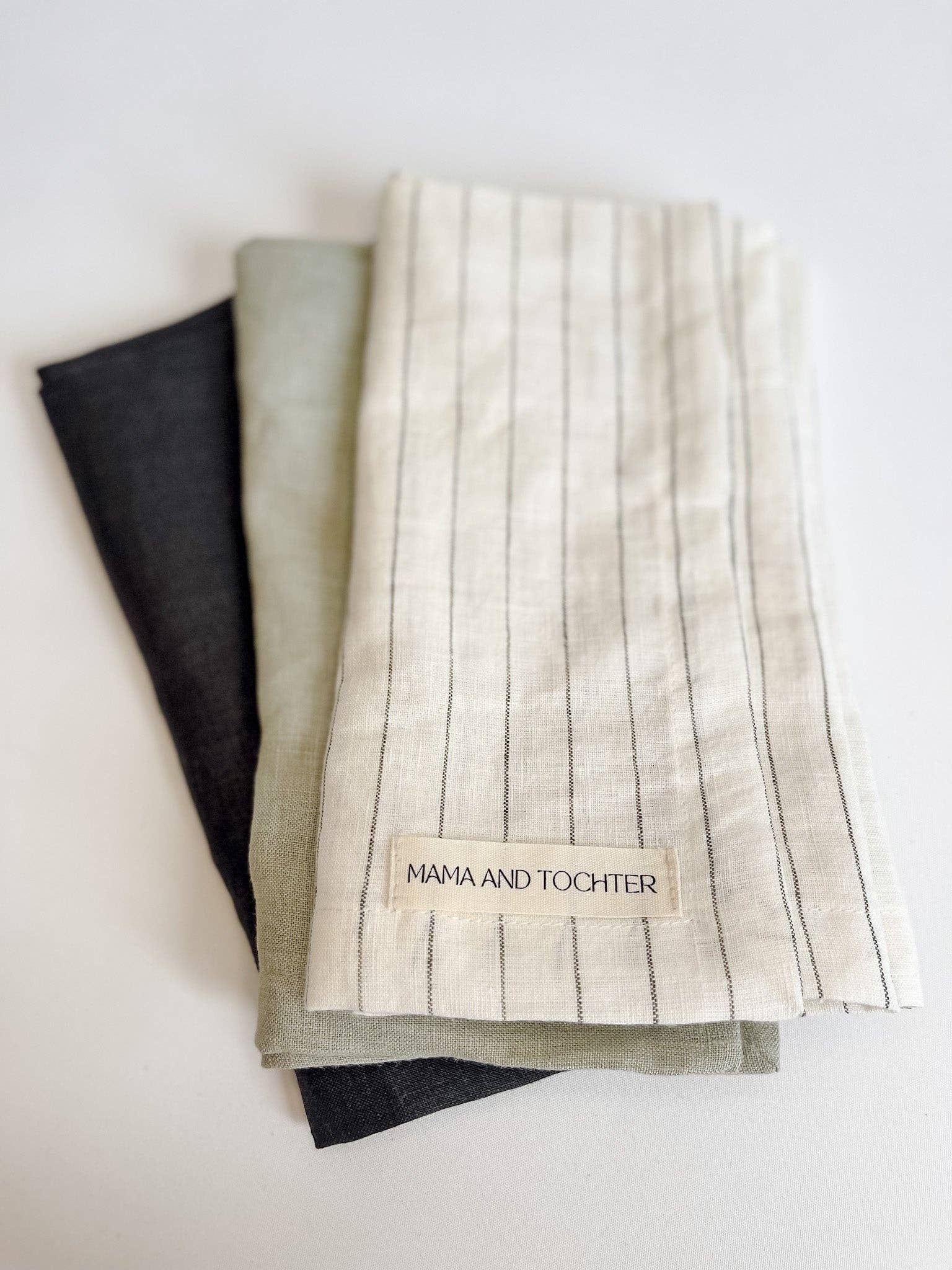 Three folded fabric towels with a visible brand label on a light background