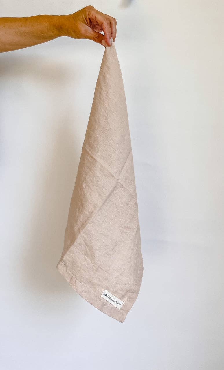 Beige towel held by a hand against a white background