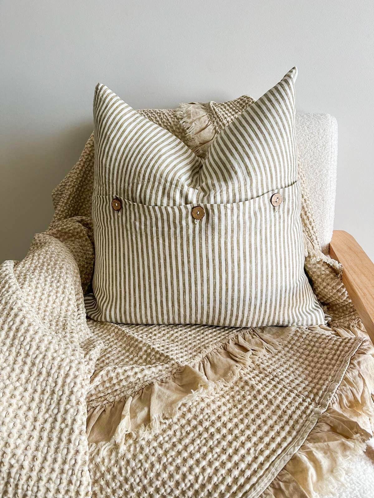 Striped pillow with buttons on a textured blanket against a neutral background