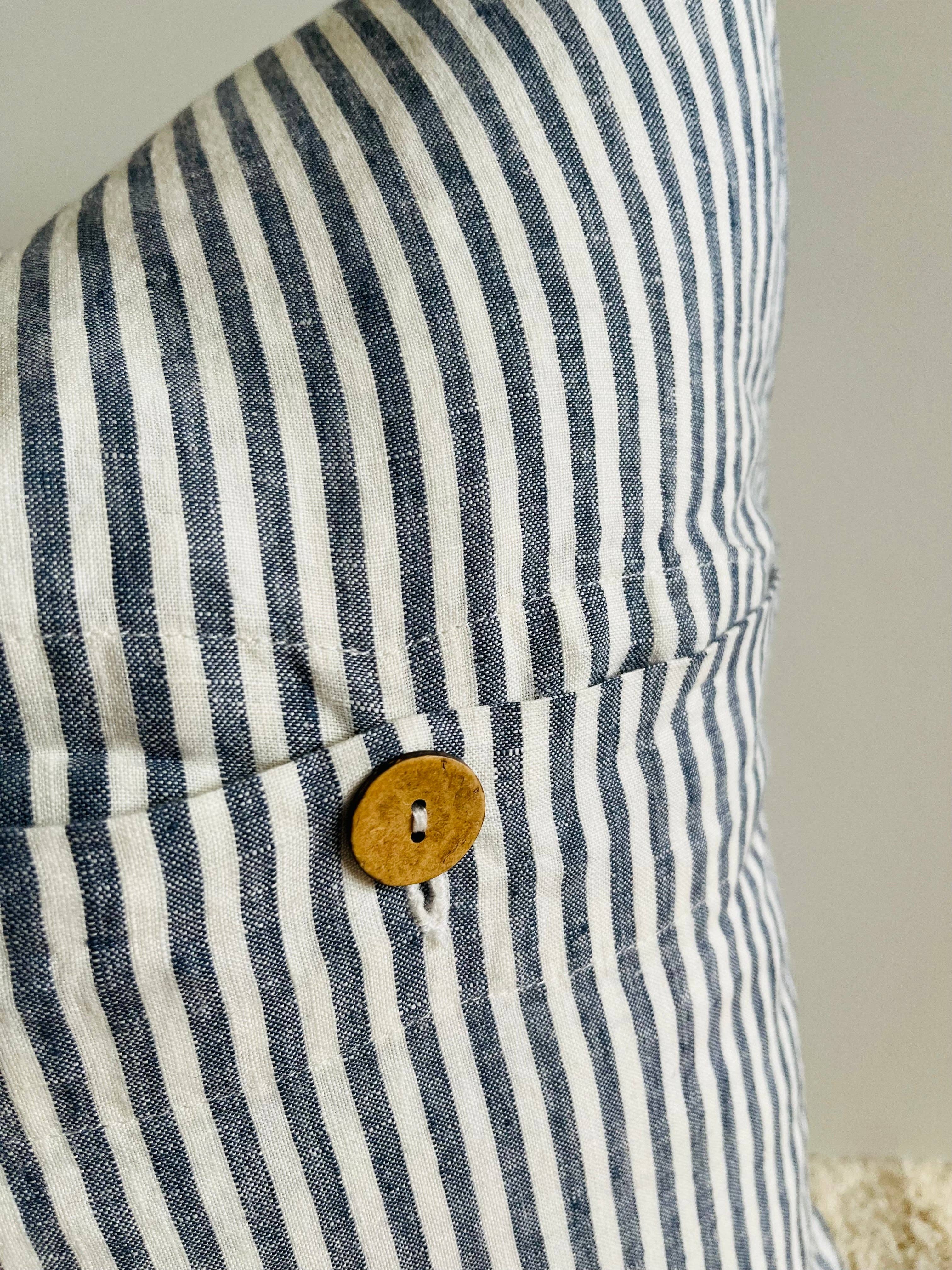 Close-up of a blue and white striped fabric with a wooden button on a neutral background