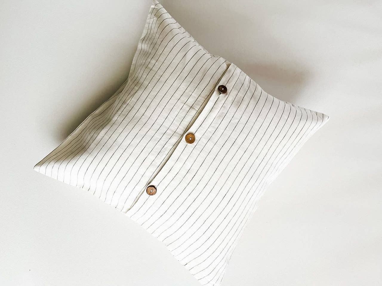 Textured pillow with wooden buttons on a light background
