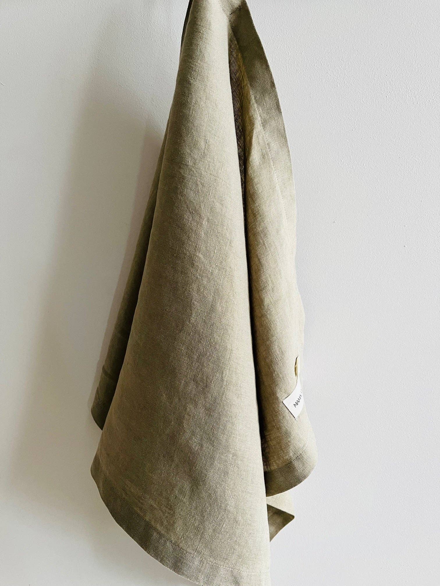 Army green towel hanging against a white wall