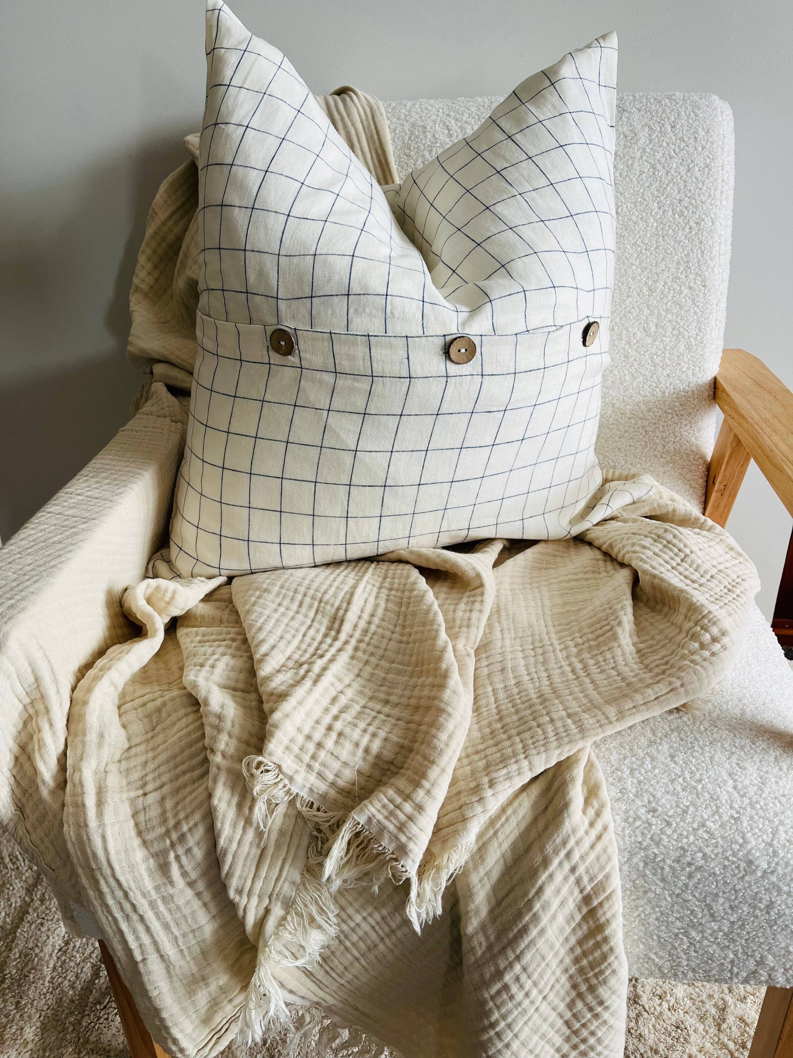 Decorative pillow with grid pattern on a chair with a blanket