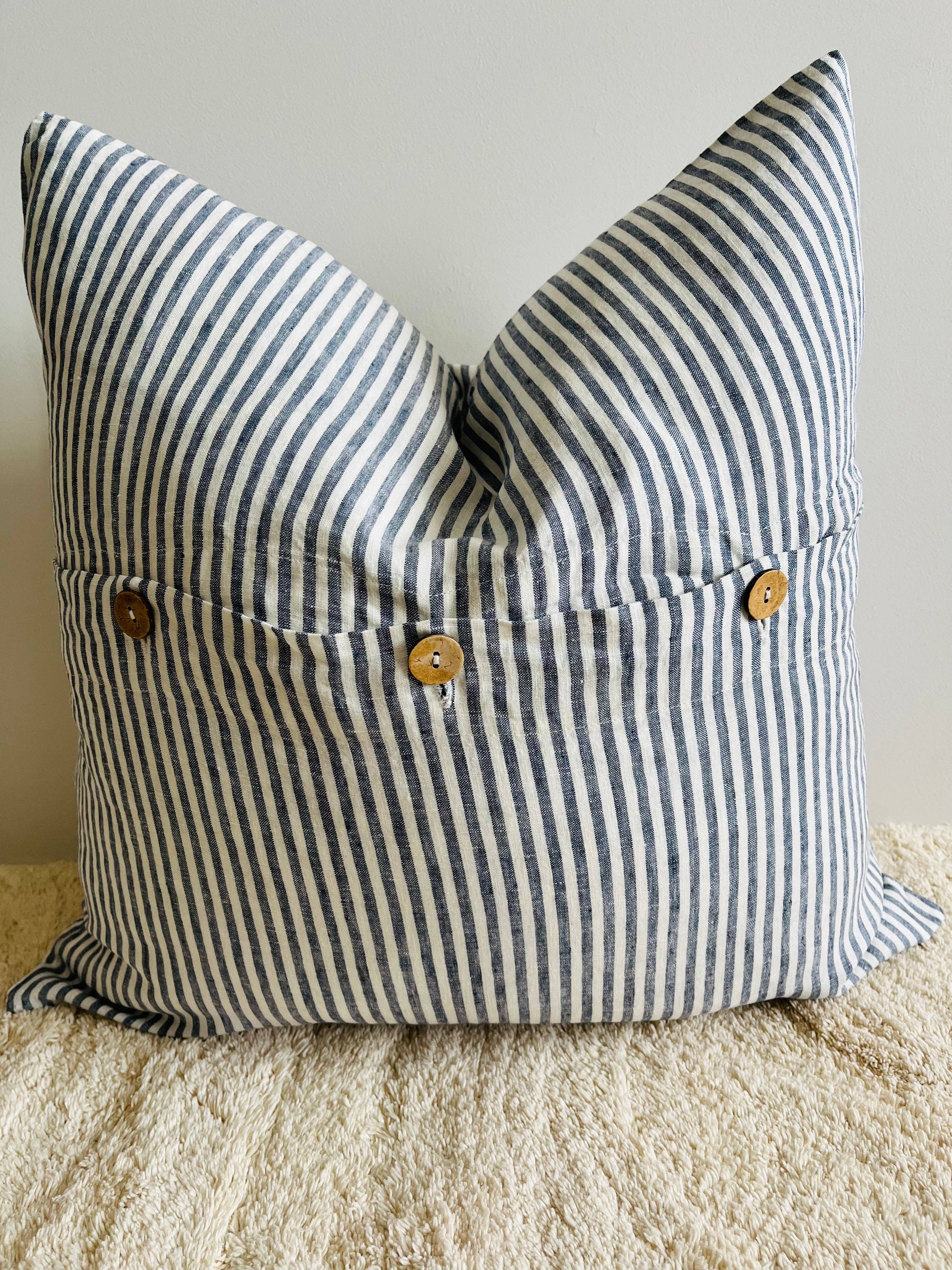 Striped pillow with button details on a neutral background