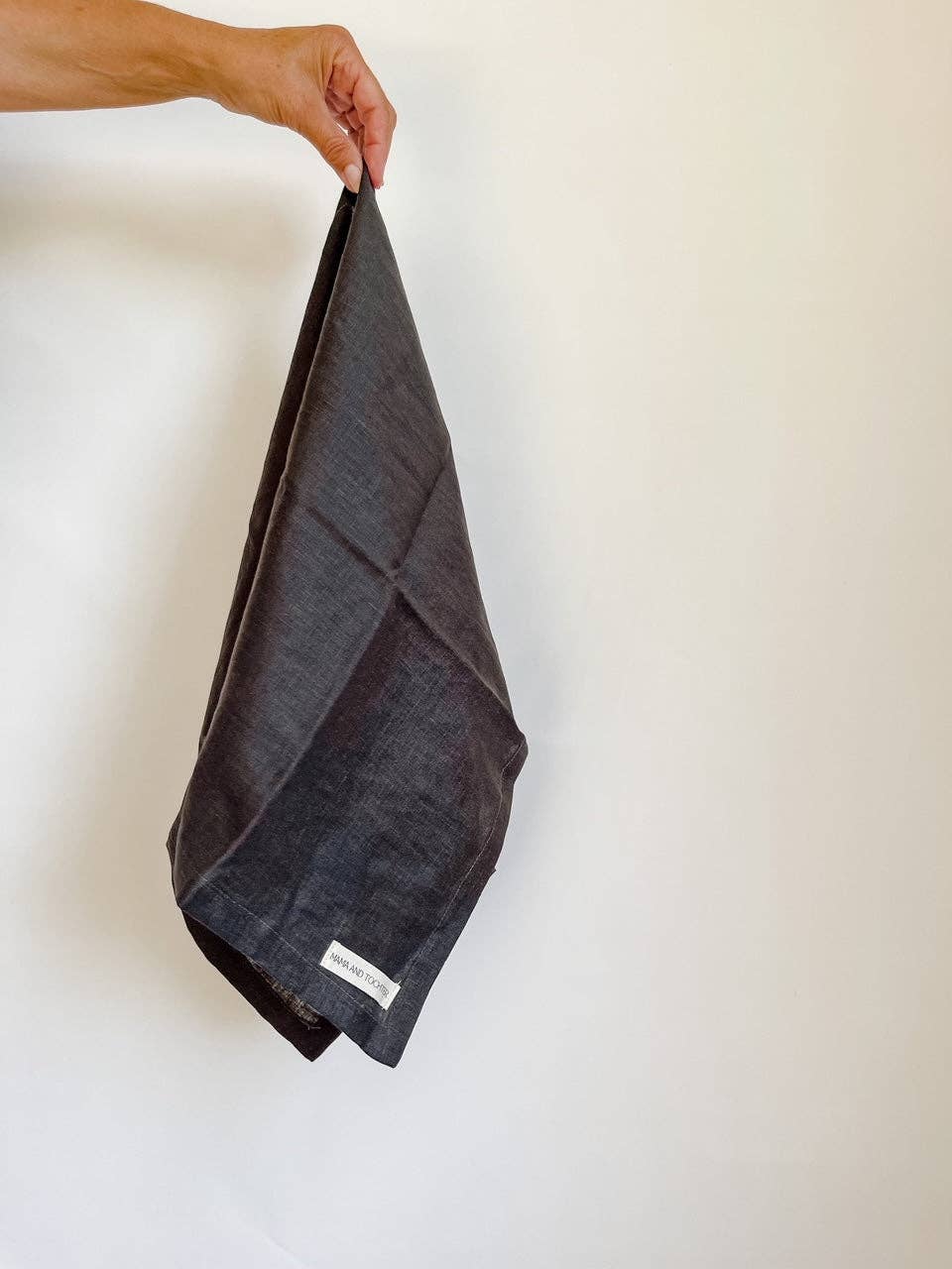 Dark gray towel held by a hand against a white background