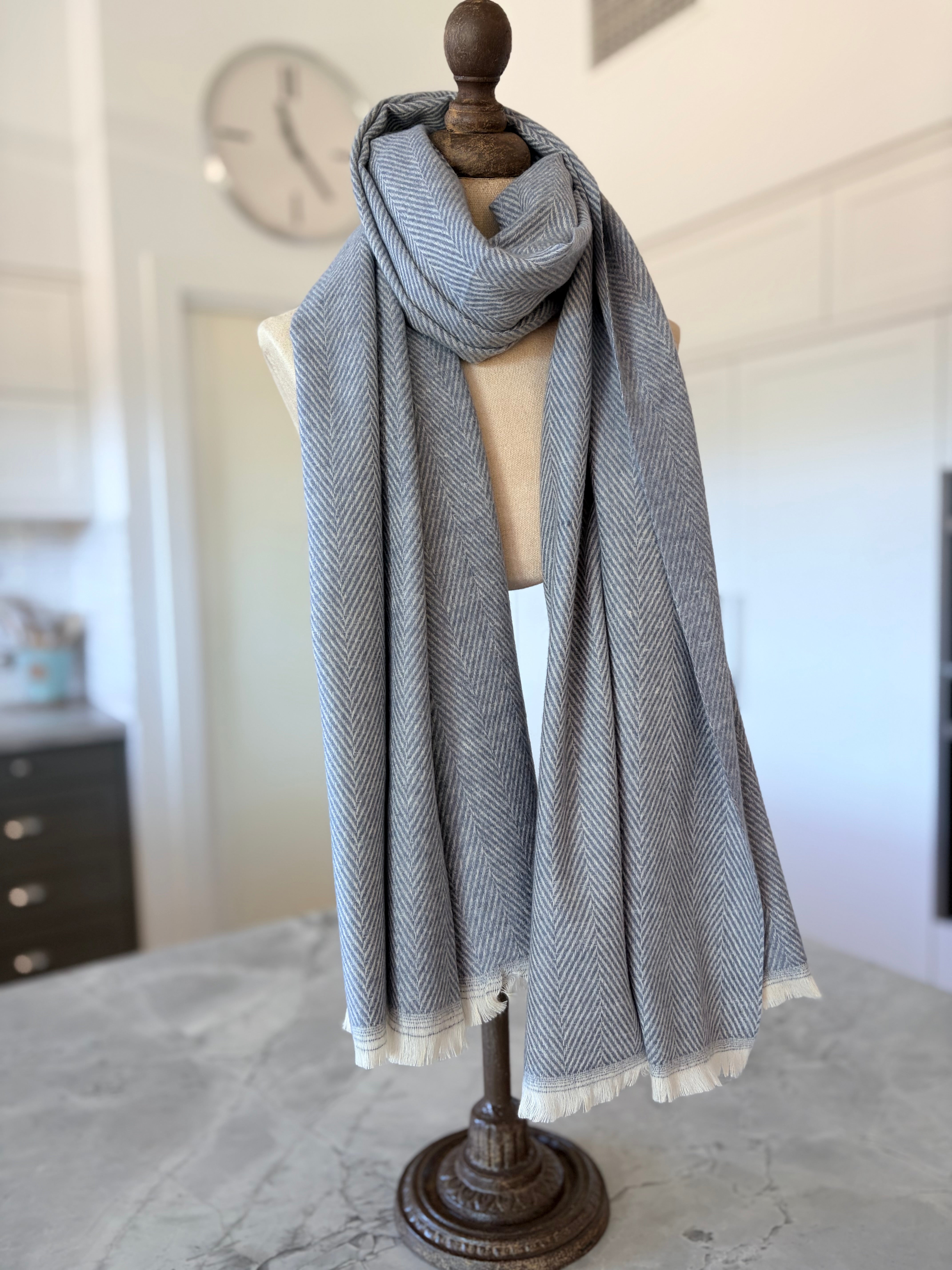 Gray herringbone scarf on a mannequin with a blurred indoor background