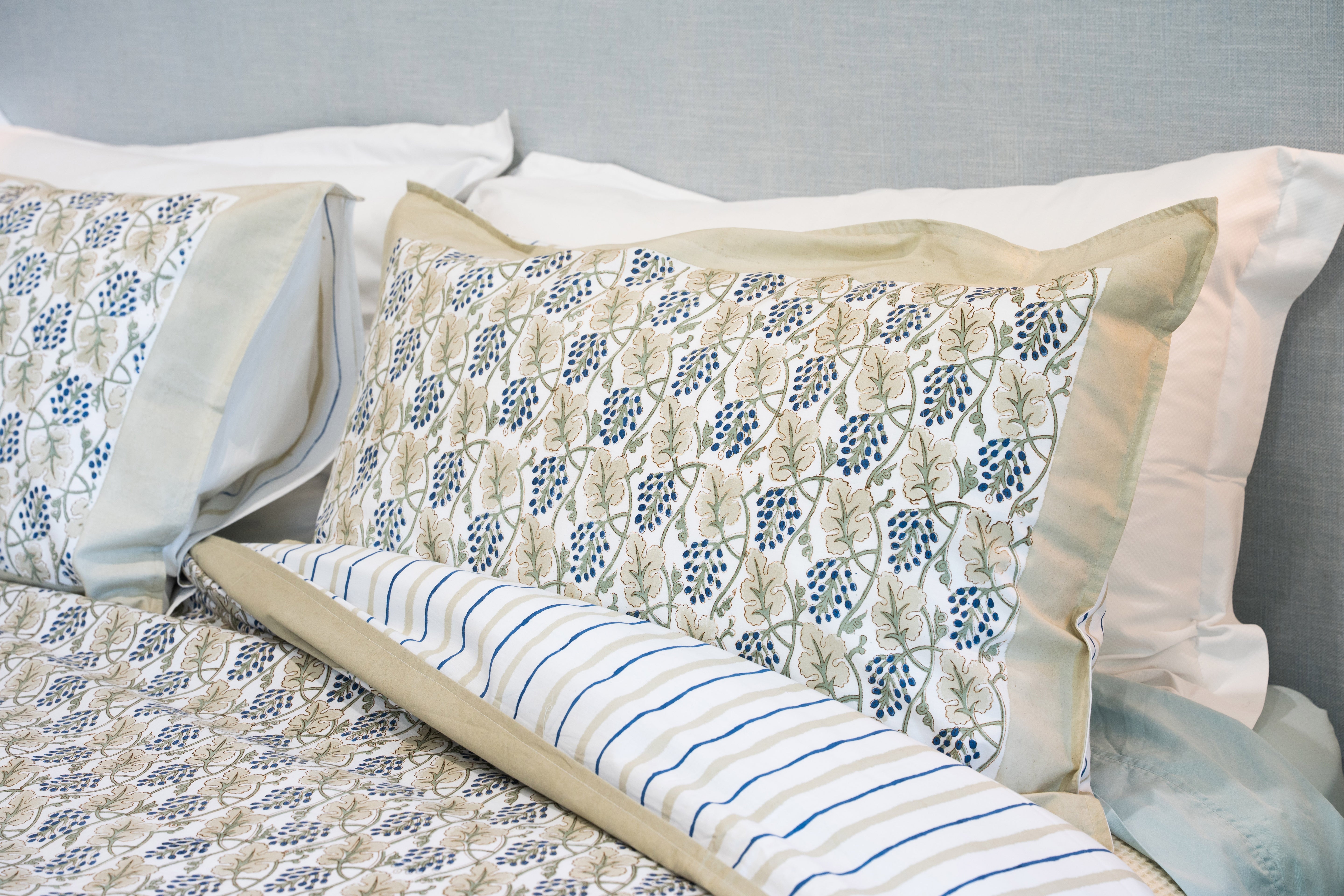 Decorative pillows with floral and striped patterns on a bed.