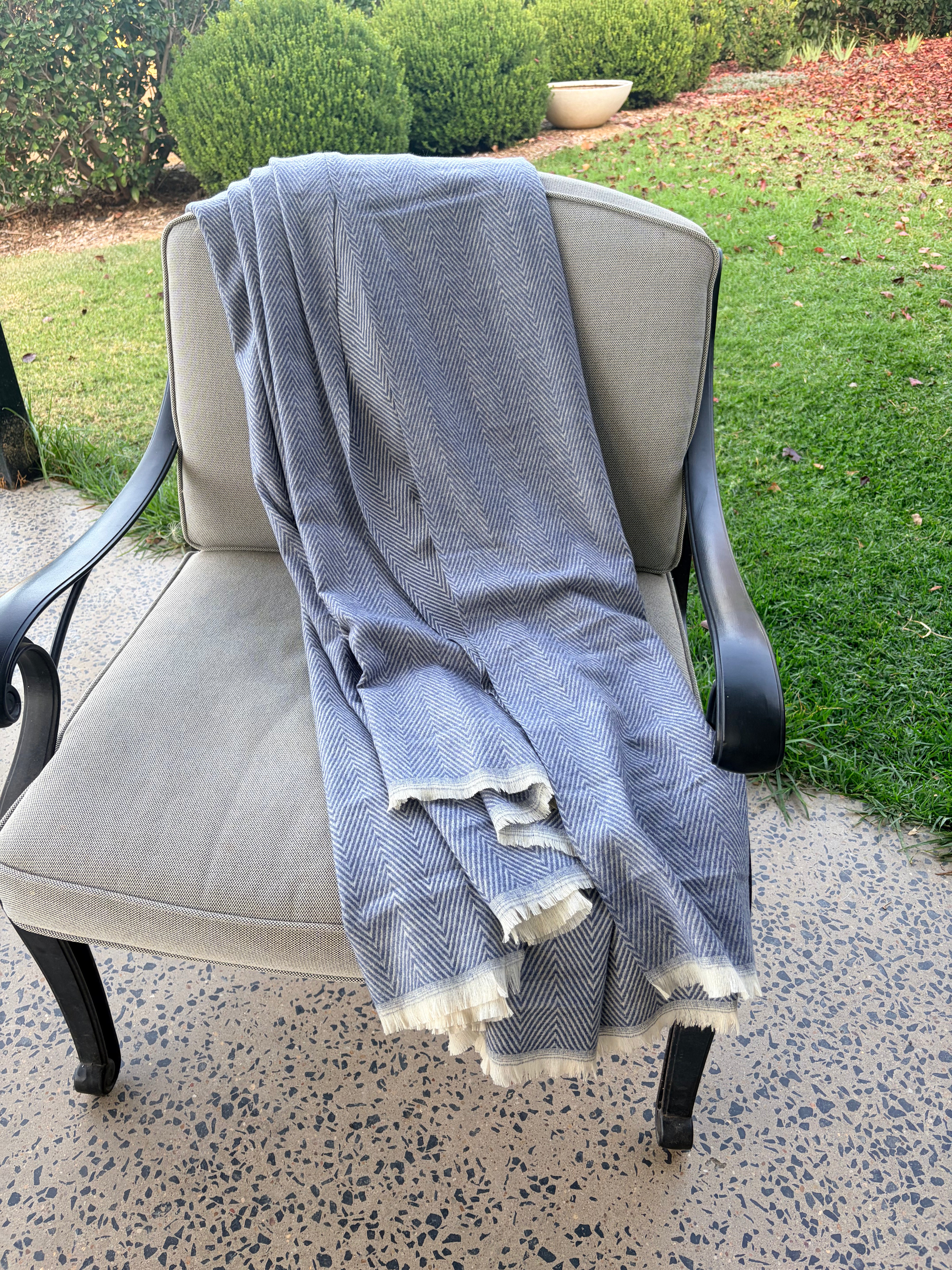 Gray checkered throw draped over a chair outdoors on a patio.