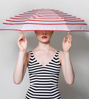Person holding a red and white striped umbrella with a plain background