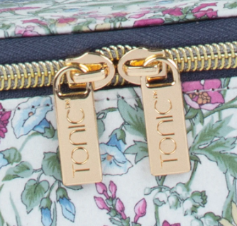 Close-up of a floral-patterned bag with gold zippers and 'Tonic' branding.