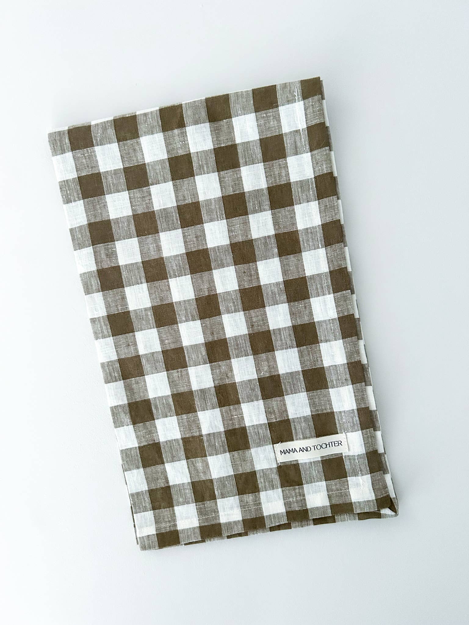 Olive green and white checkered towel on a light gray background
