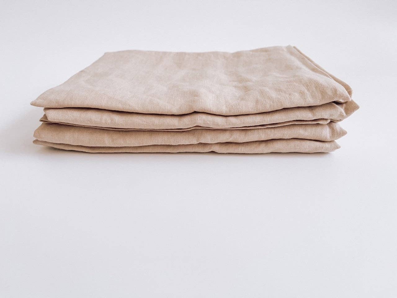 Folded light clay tea towels on a light background