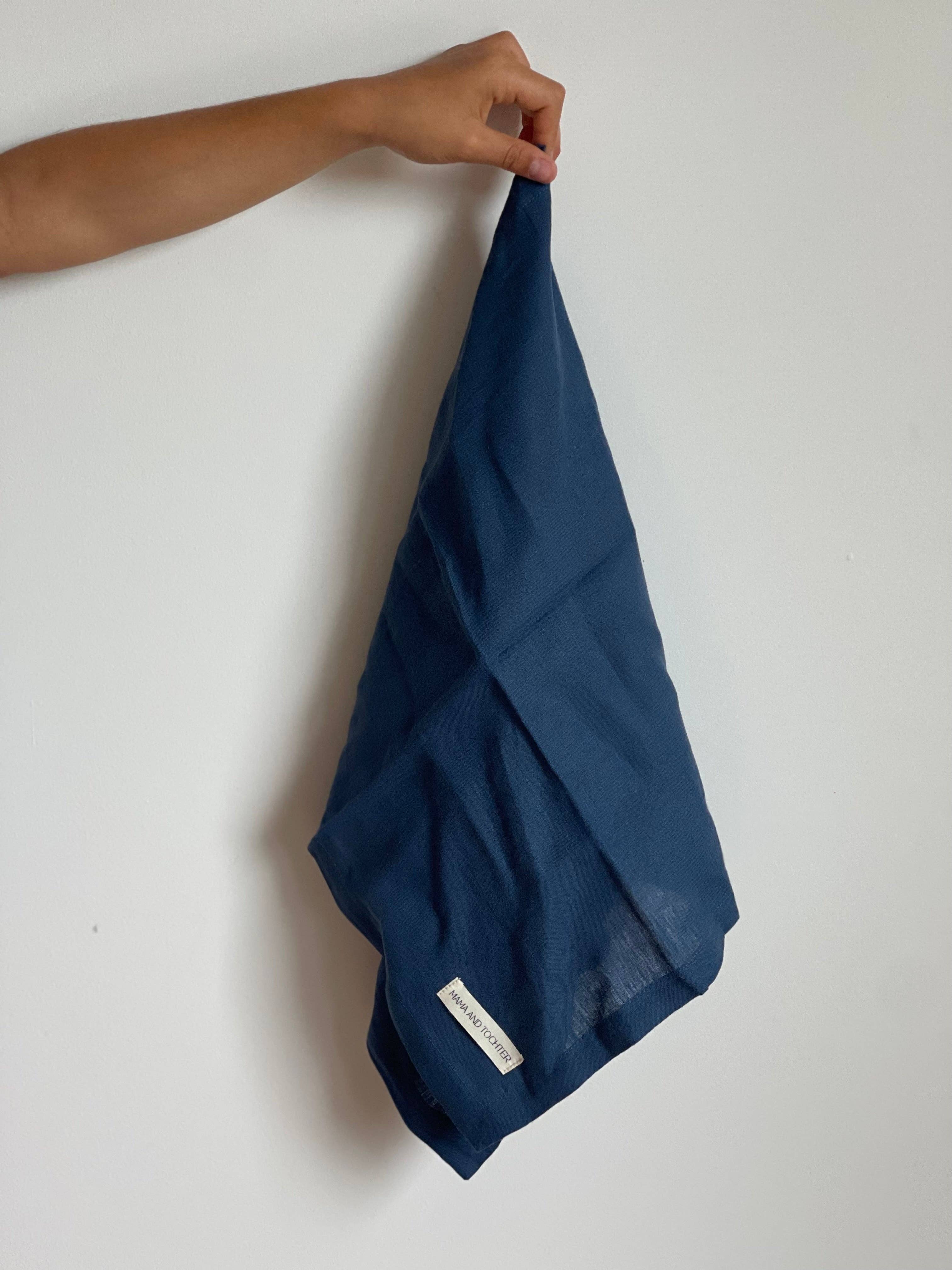Dark blue towel held by a hand on a white background