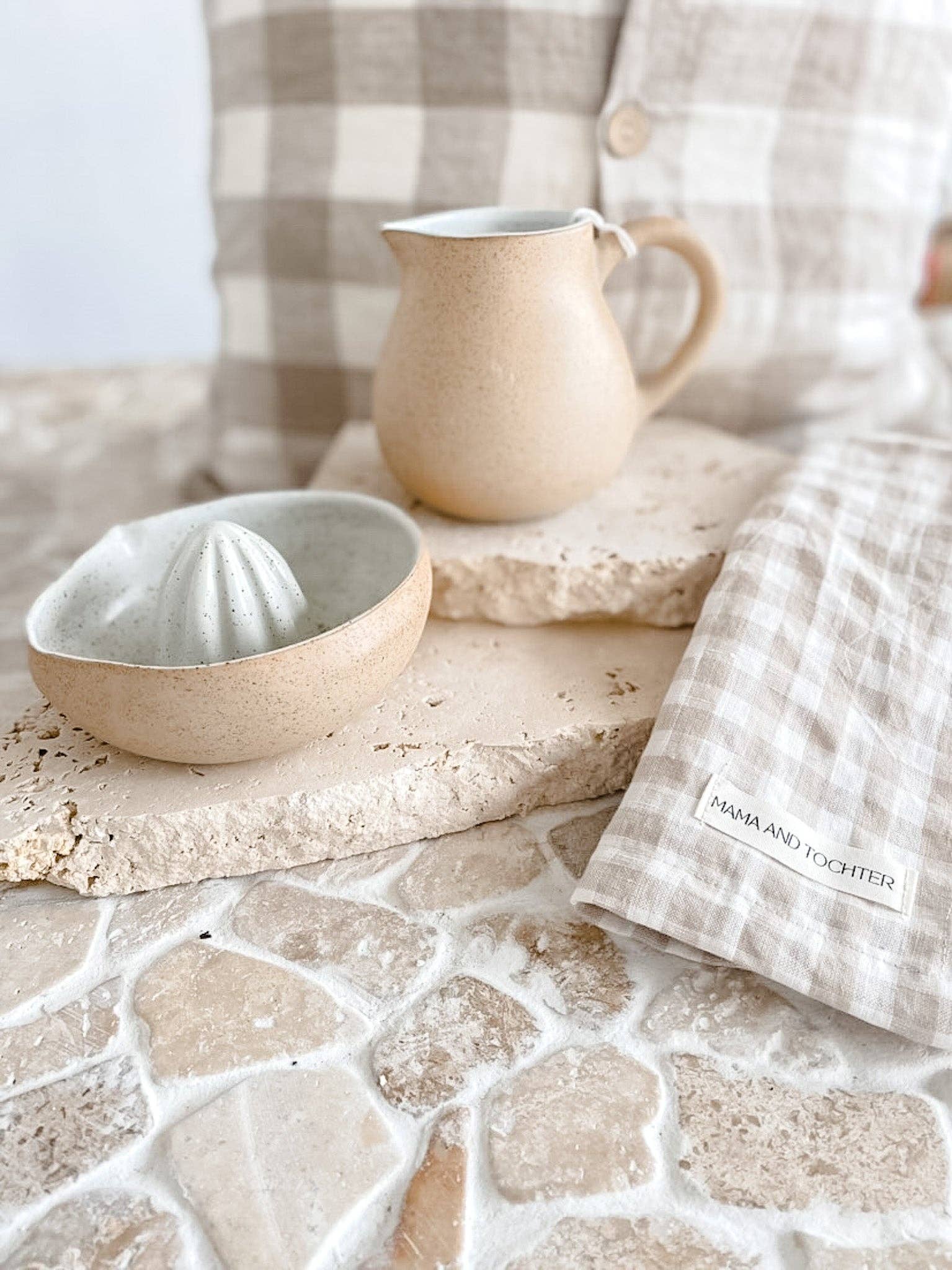 Ceramic pitcher and bowl on a stone surface with a checkered cloth in the background